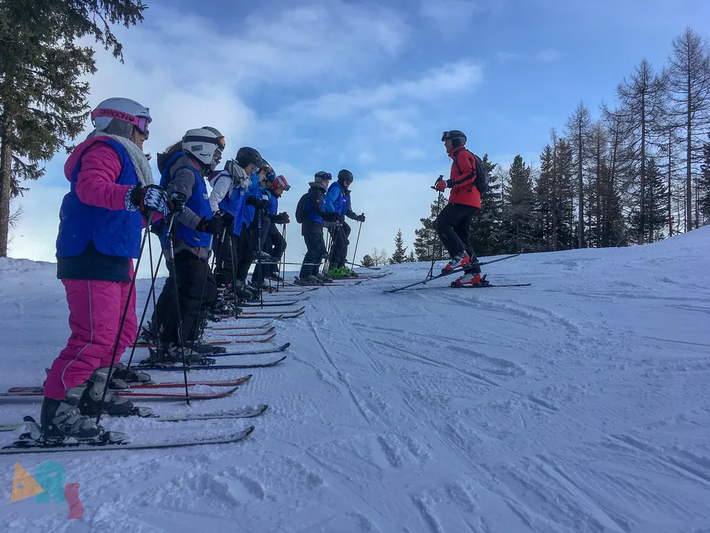 Skigruppe steht in einer Reihe vor dem Wald.